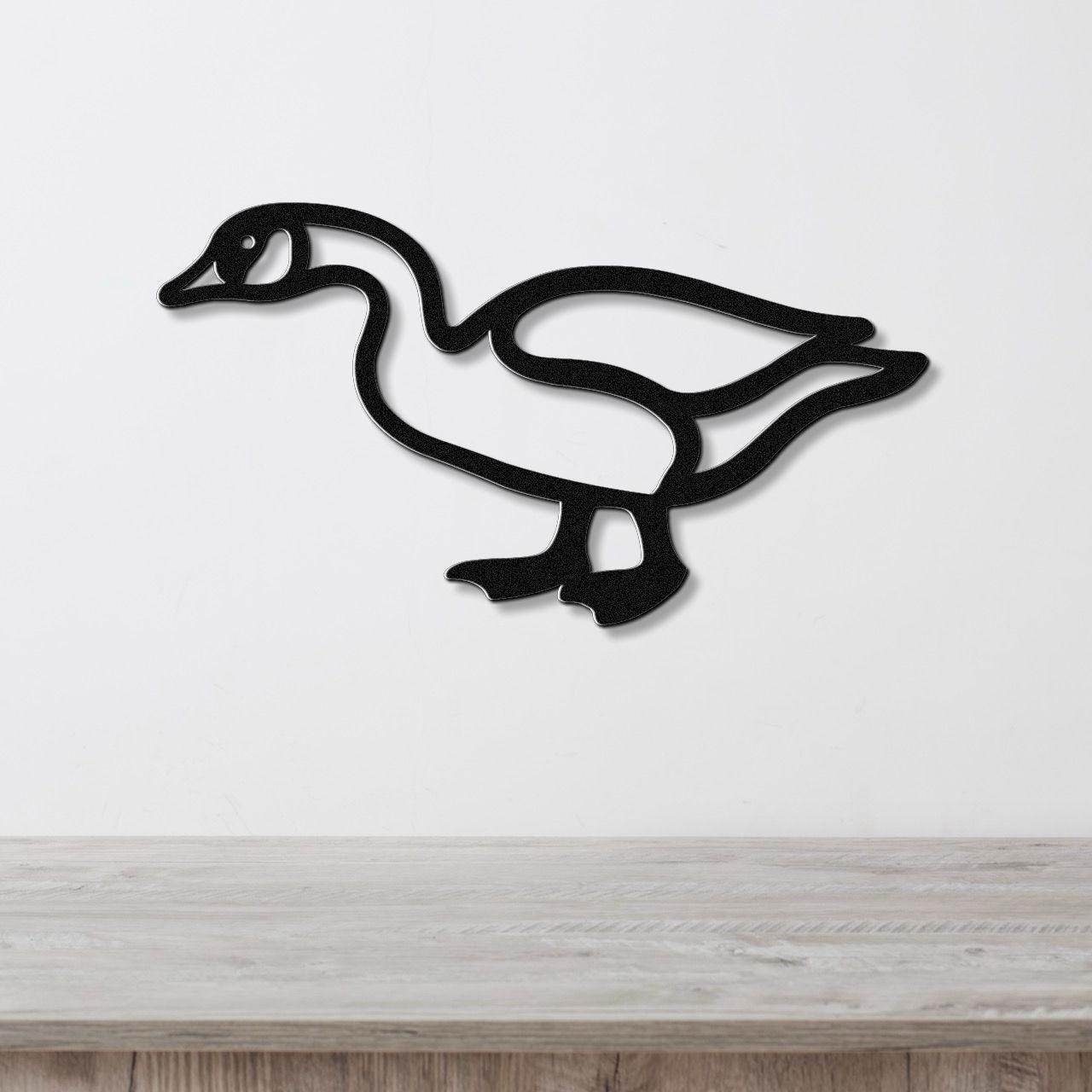 Black metal goose wall art silhouette with cutout details, mounted on a white wall above a light wood surface.