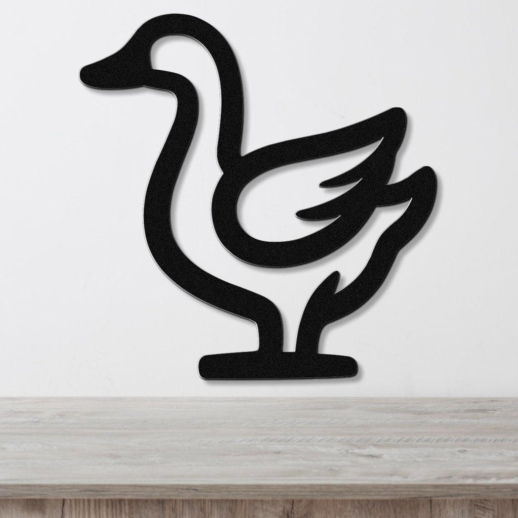 Black metal goose wall art silhouette with cutout wing and neck details, mounted on a white wall above a light wood surface.