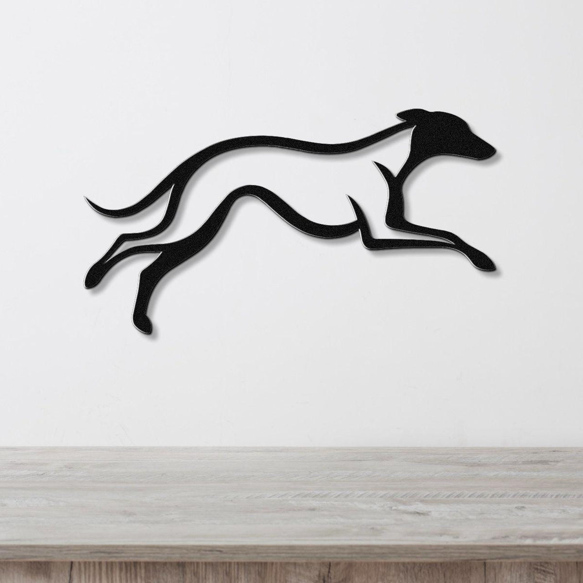Black metal greyhound wall art with motion-line cutouts, mounted on a white wall above a light wood counter.
