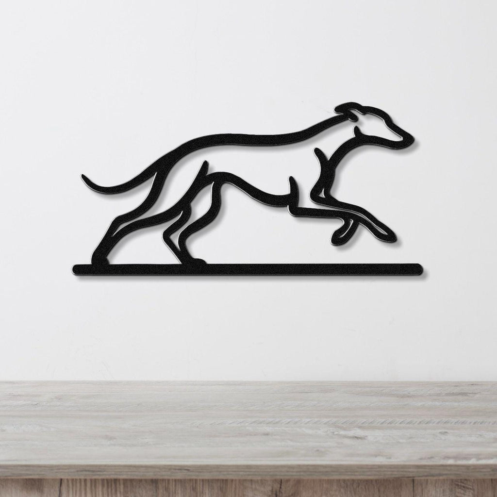 Black metal wall art featuring a greyhound silhouette in motion, mounted on a white wall above a wooden surface.