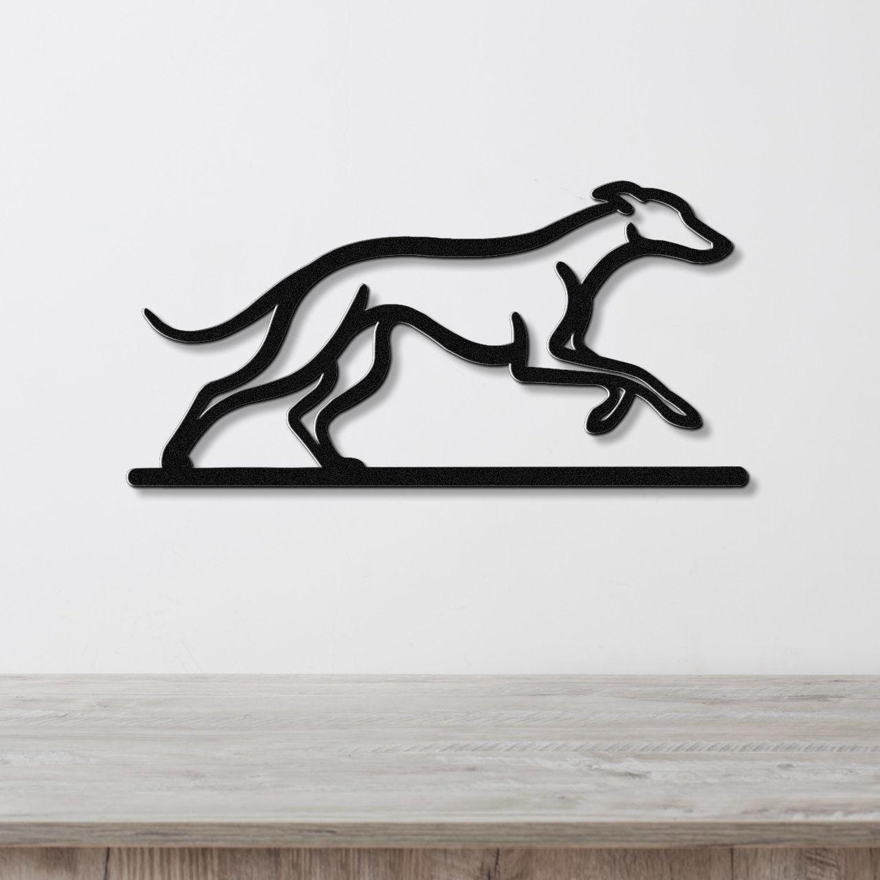 Black metal wall art featuring a greyhound silhouette in motion, mounted on a white wall above a wooden surface.