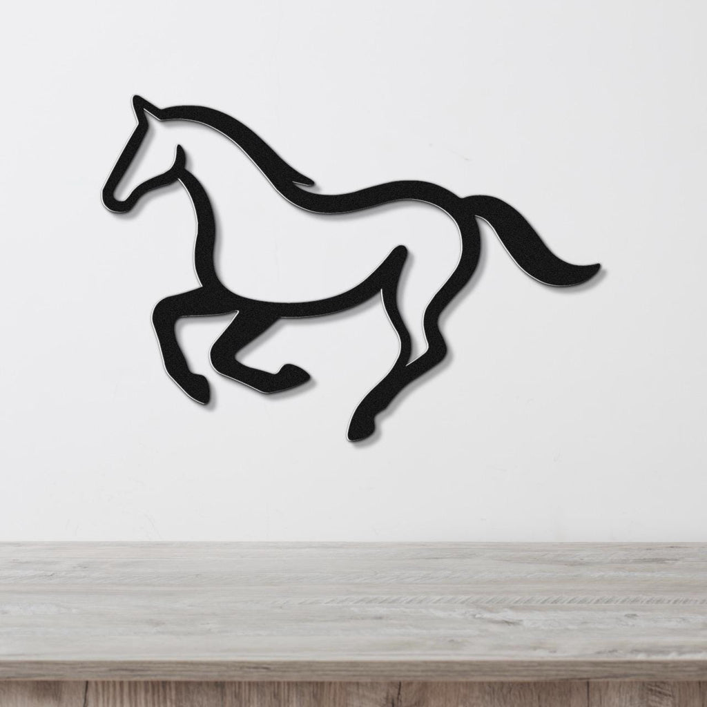 Black metal horse wall art in a running silhouette, mounted on a white wall above a light wood counter.