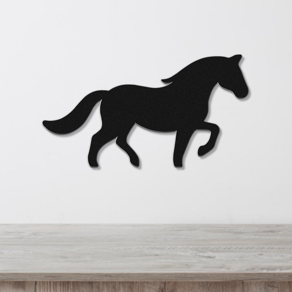 Black metal horse silhouette wall art with a dynamic running pose, mounted on a white wall above a light wood surface.