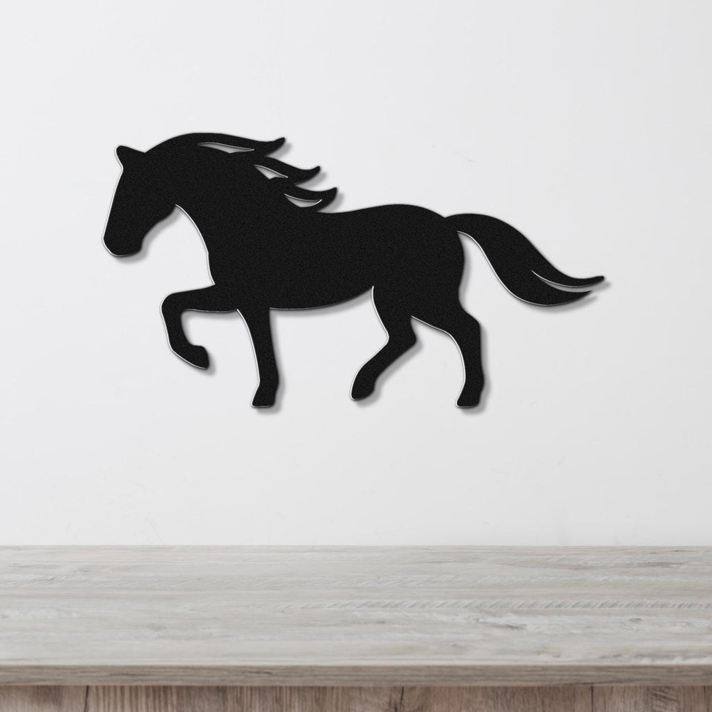 Black metal horse wall art silhouette with flowing mane and tail cutouts, mounted on a white wall above a light wood surface.