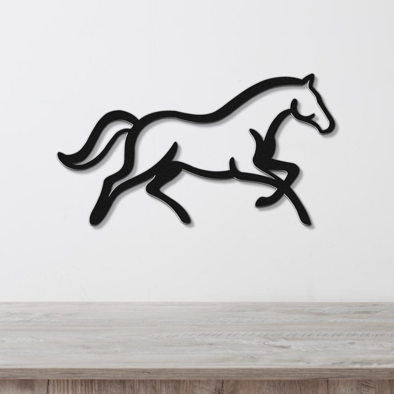 Black metal horse wall art with a running silhouette, mounted on a white wall above a light wood surface.
