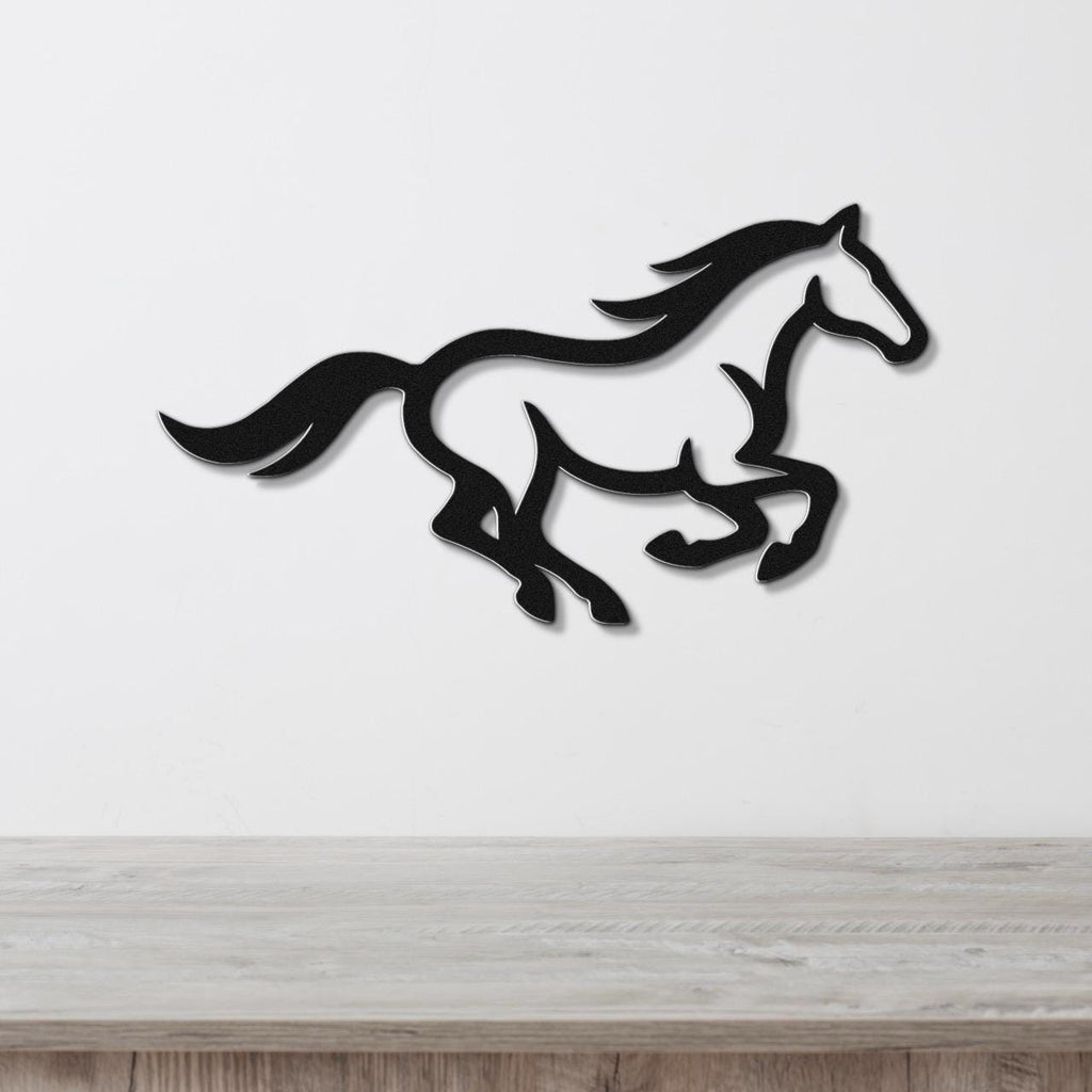 Black metal horse wall art in a running silhouette, mounted on a white wall above a light wood counter.