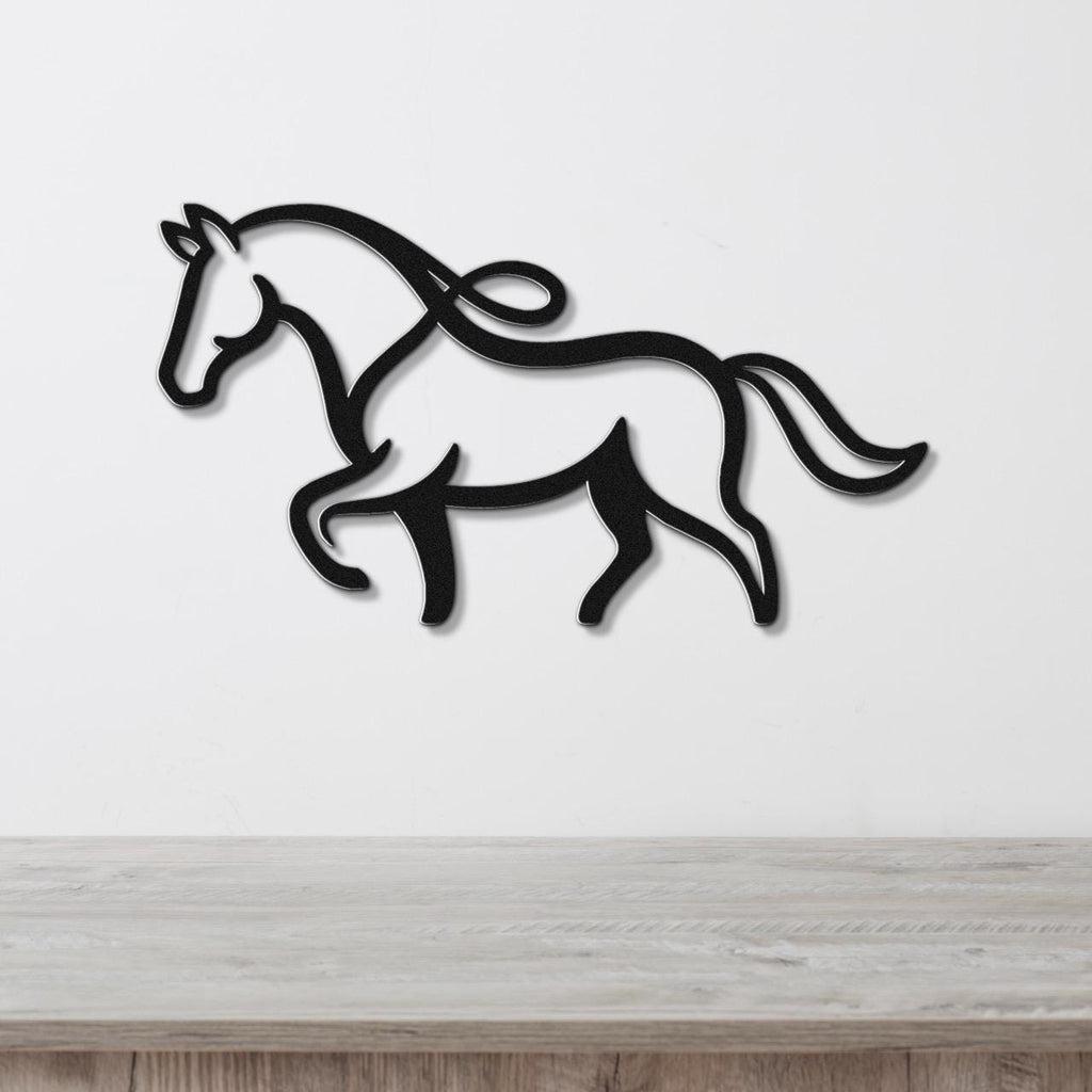 Black metal horse wall art with flowing mane and tail cutouts, mounted on a white wall above a light wood surface.