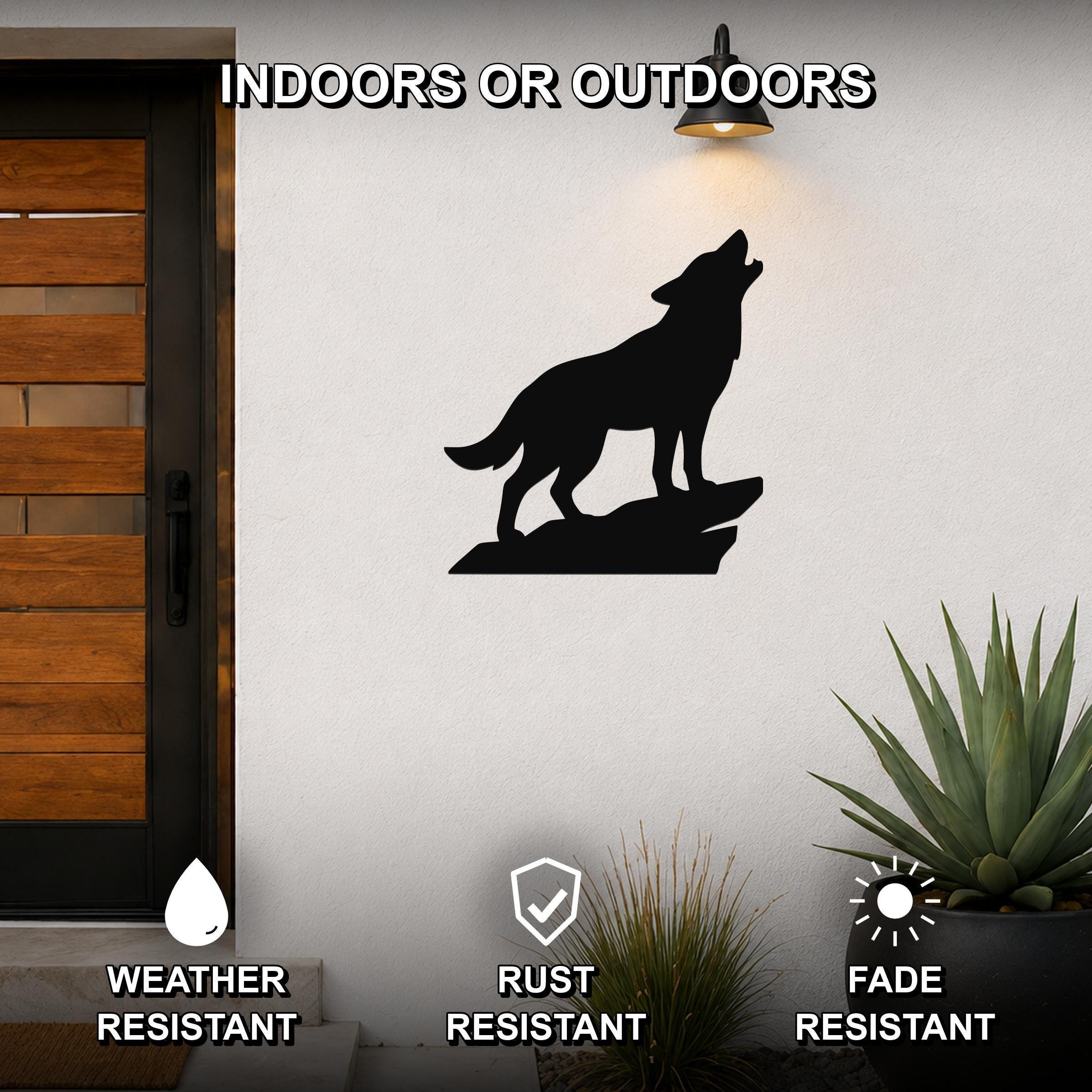 Black metal coyote wall art silhouette howling on a rock, mounted on an outdoor wall beside a wooden door and potted plants.