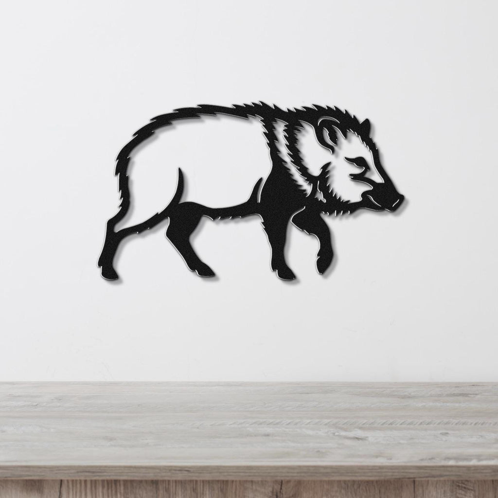 Black metal javelina wall art silhouette with detailed fur and facial features, mounted on a white wall above a light wood surface.