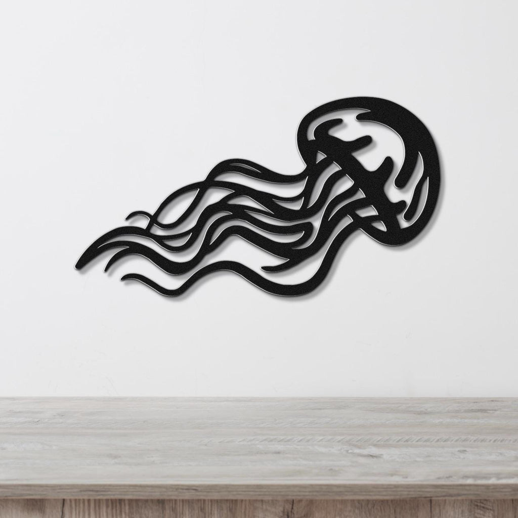 Black metal jellyfish wall art with flowing tentacle cutouts, mounted on a white wall above a light wood counter.