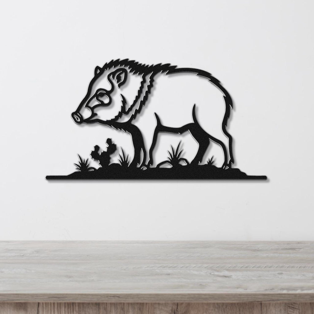 Black metal wall art silhouette of a javelina with grass cutouts, mounted on a white wall above a wooden surface.