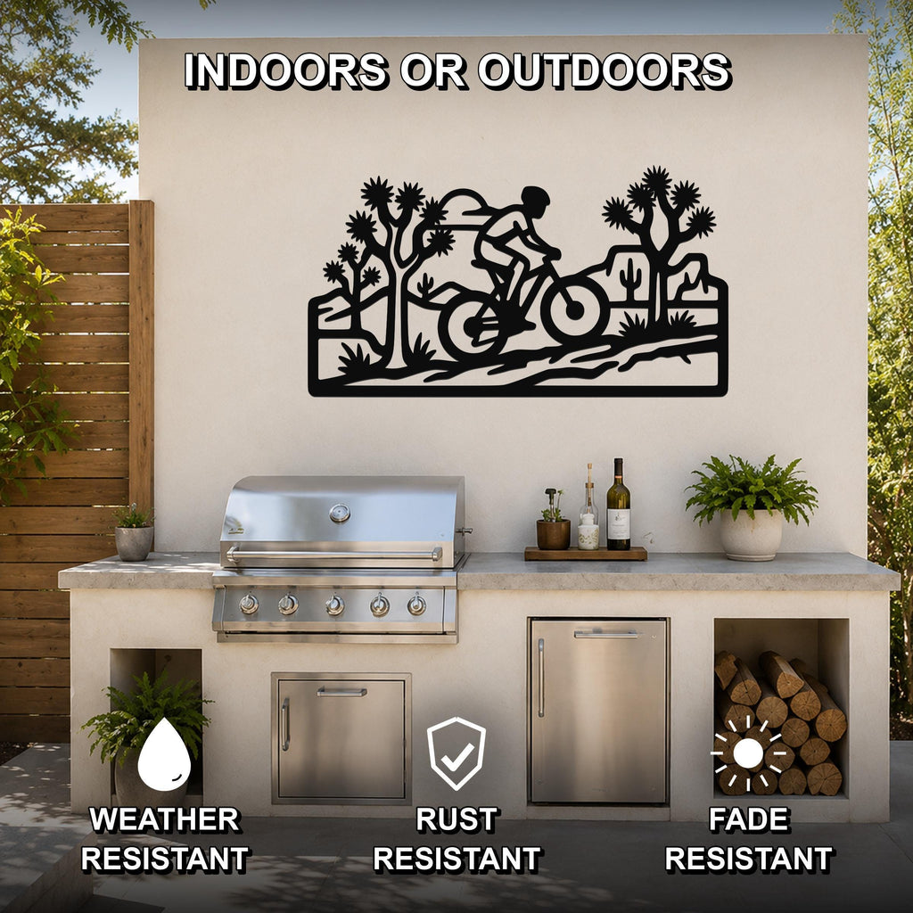 Black metal wall art featuring a cyclist silhouette and Joshua trees in a desert scene, mounted on an outdoor patio wall above a grill and counter.