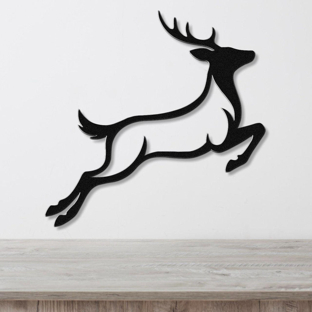 Black metal wall art of a leaping deer silhouette with antlers and motion lines, mounted on a white wall above a light wood surface.