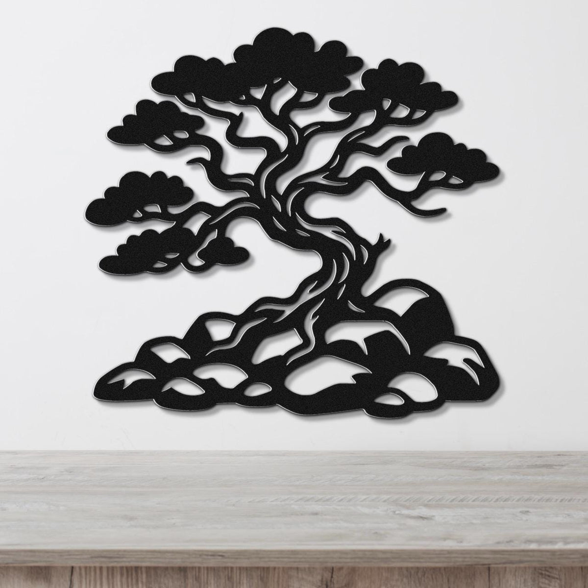 Black metal wall art silhouette of a juniper tree with intricate branches and roots, mounted on a white wall above a wooden counter.
