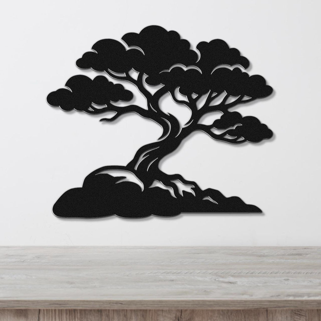 Black metal wall art cutout of a juniper tree with detailed branches and roots, mounted on a white wall above a wooden surface.
