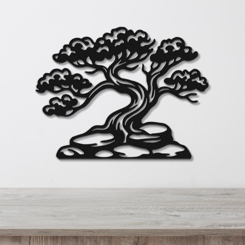 Black metal wall art cutout of a juniper tree with detailed branches and foliage, mounted on a white wall above a wooden surface.
