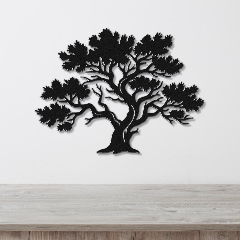 Black metal juniper tree wall art with detailed branch and leaf cutouts, mounted on a white wall above a light wood counter.