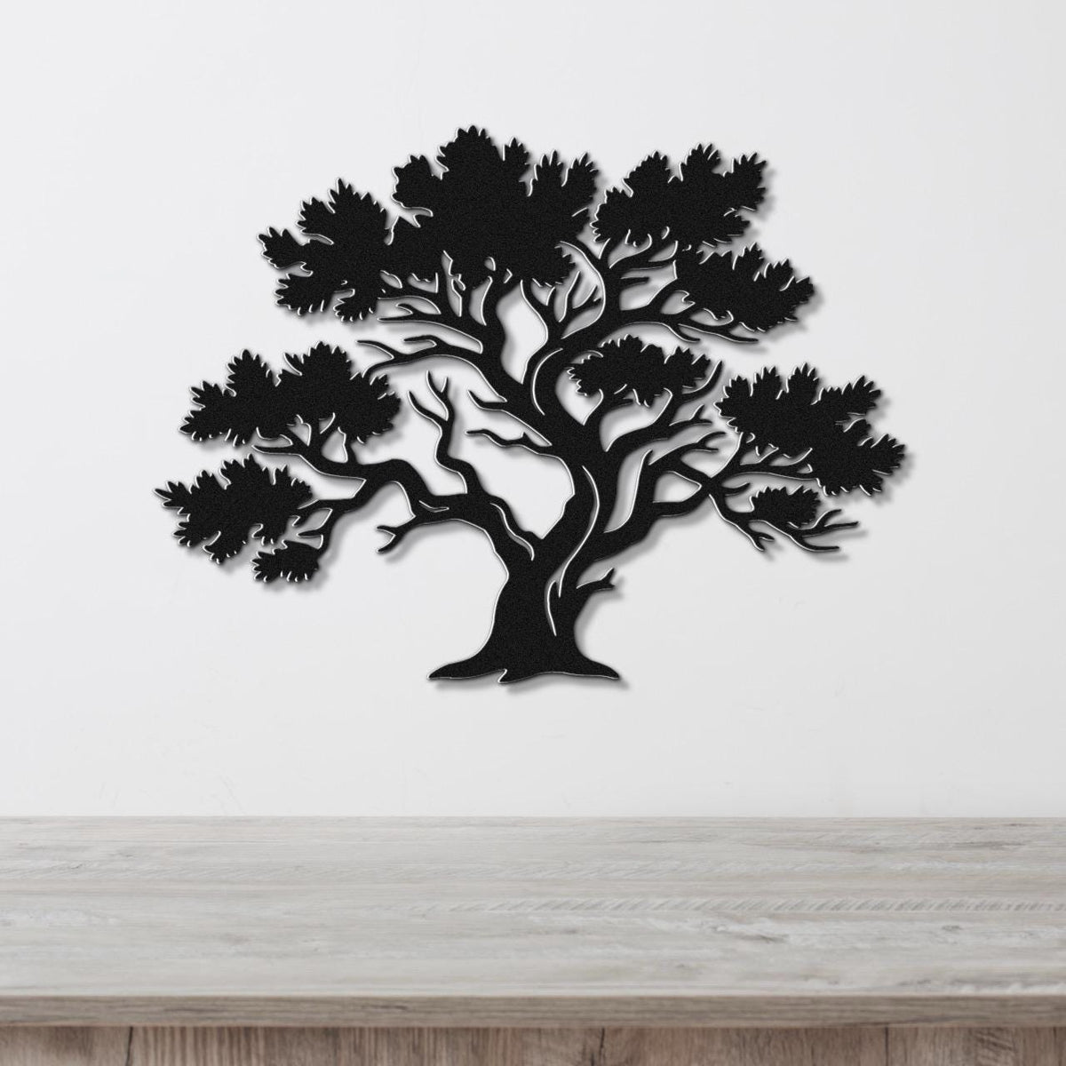 Black metal juniper tree wall art with detailed branch and leaf cutouts, mounted on a white wall above a light wood counter.