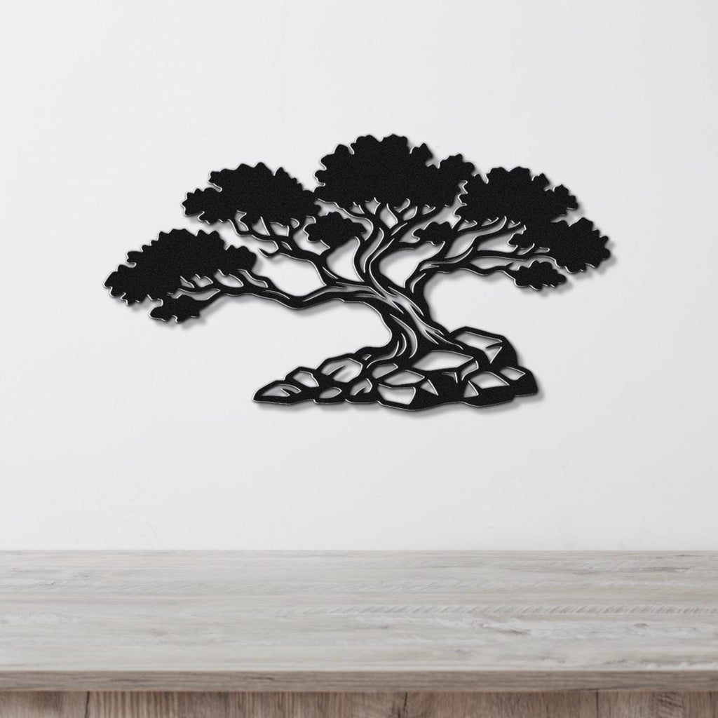 Black metal wall art cutout of a juniper tree with detailed branches and roots, mounted on a white wall above a wooden surface.