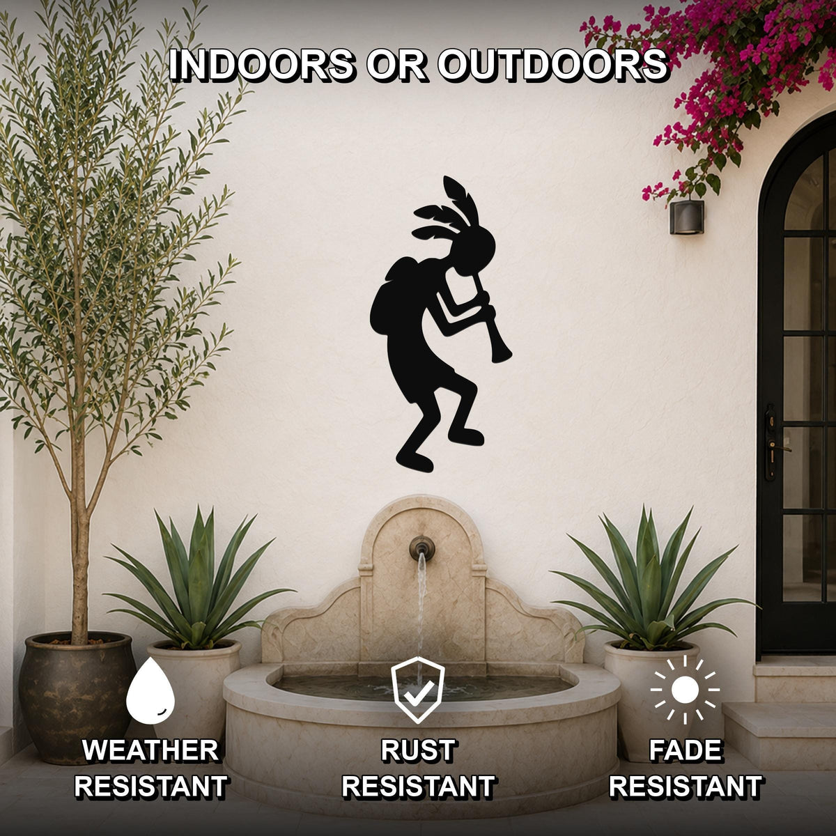 Black metal Kokopelli wall art silhouette playing a flute, mounted on an outdoor patio wall above a stone fountain, flanked by potted plants.