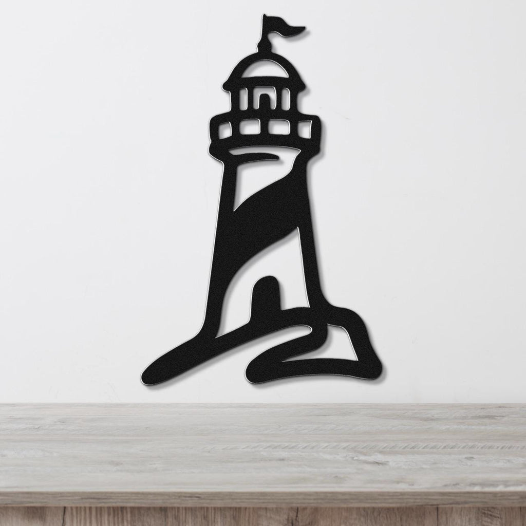 Black metal lighthouse wall art with a flag cutout at the top, mounted on a white wall above a wooden surface.
