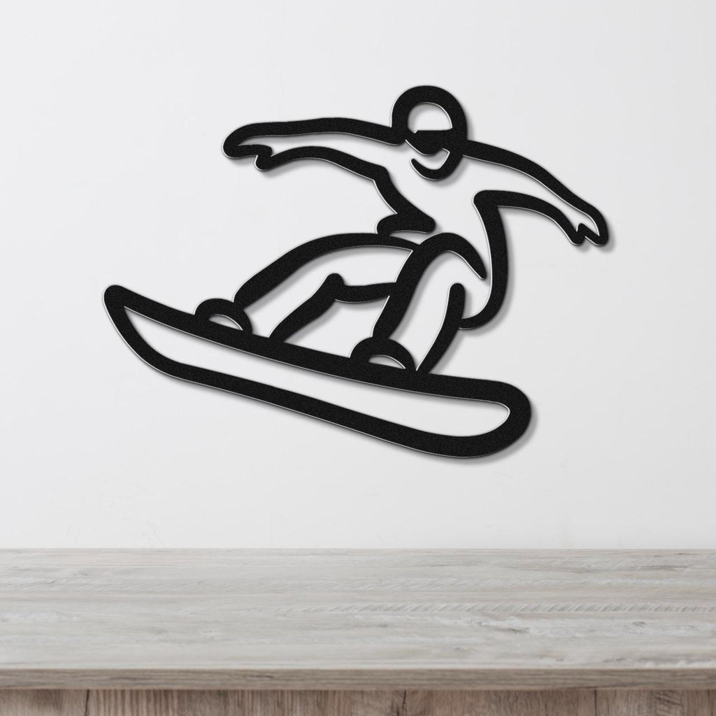 Black metal wall art cutout of a snowboarder in motion, mounted on a white wall above a light wood surface.