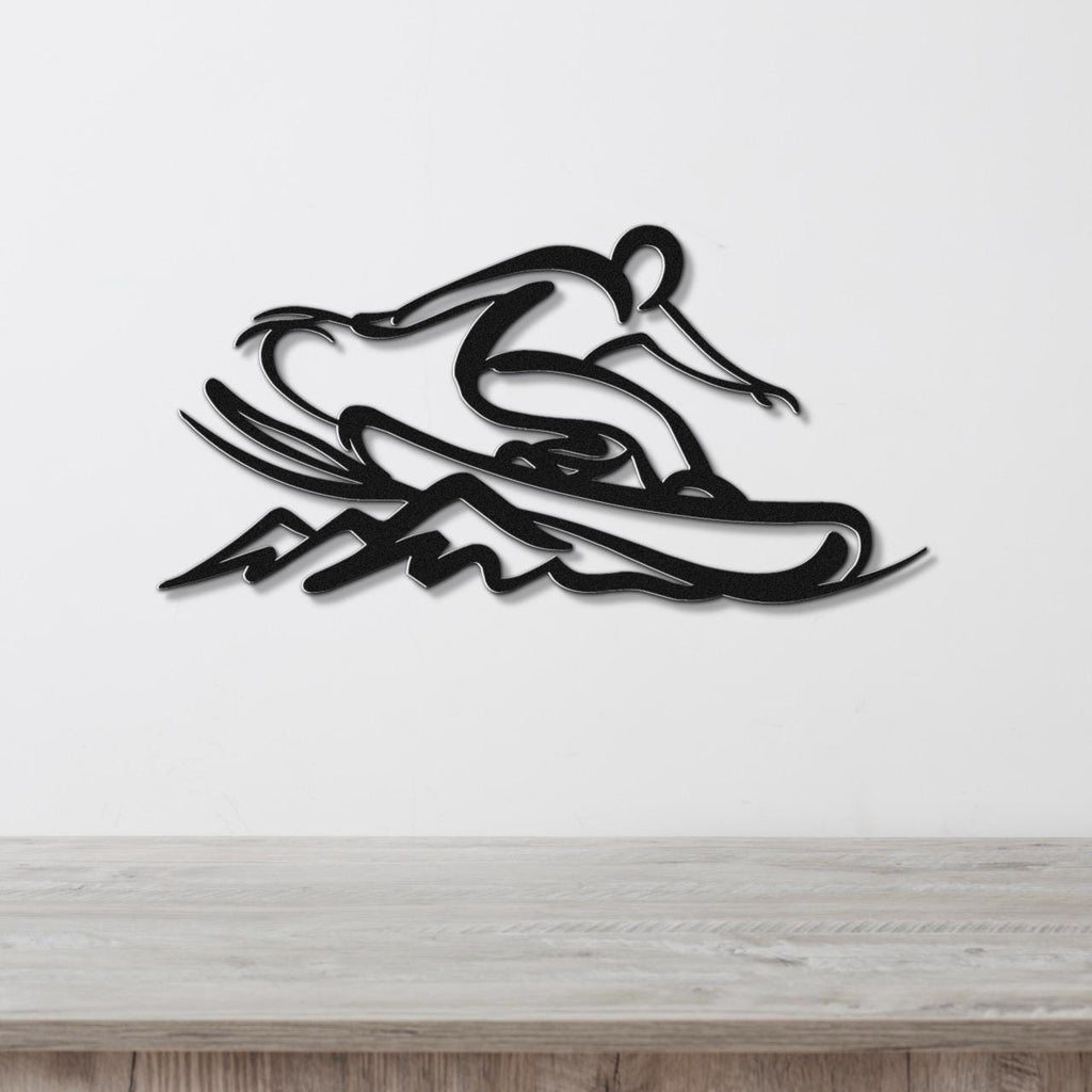 Black metal wall art silhouette of a snowboarder in motion, mounted on a white wall above a light wood surface.