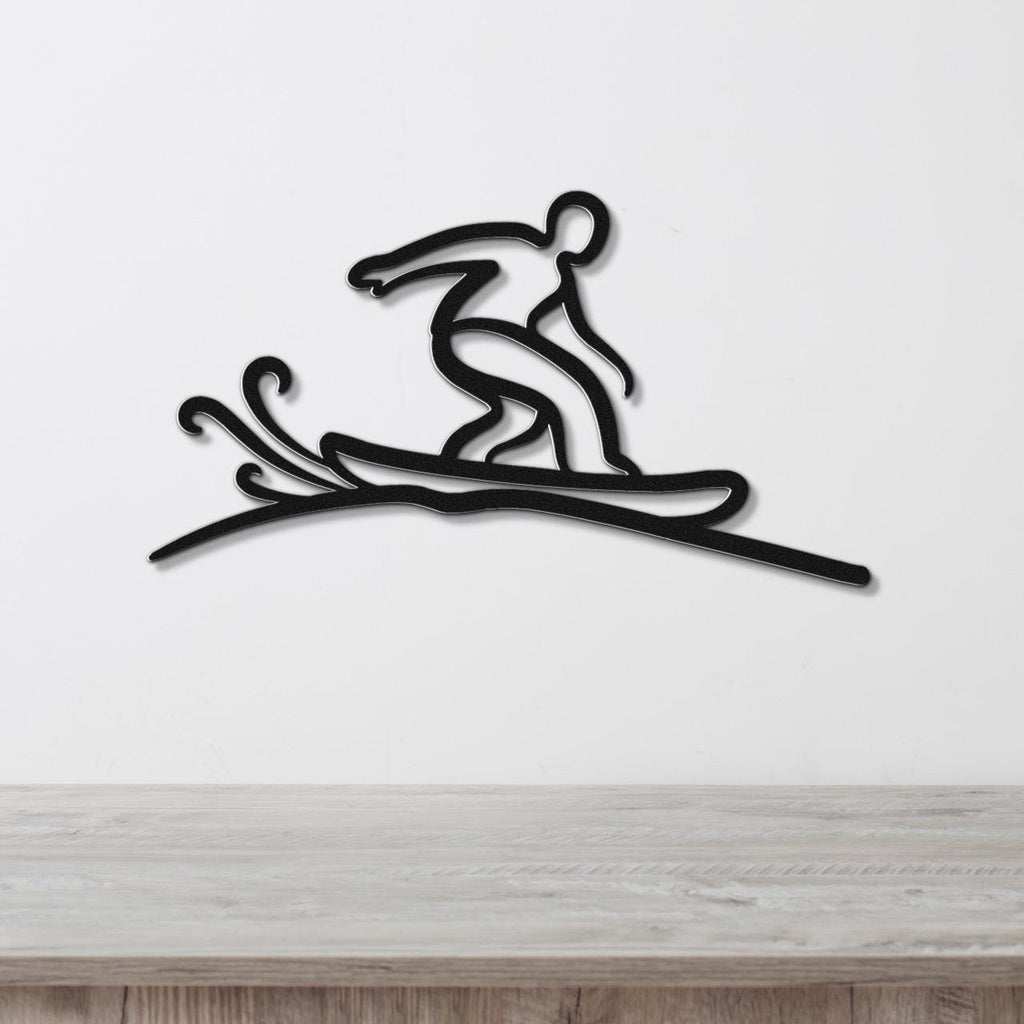 Black metal wall art silhouette of a snowboarder in motion, with dynamic cutout lines for snow spray, mounted on a white wall above a wooden surface.