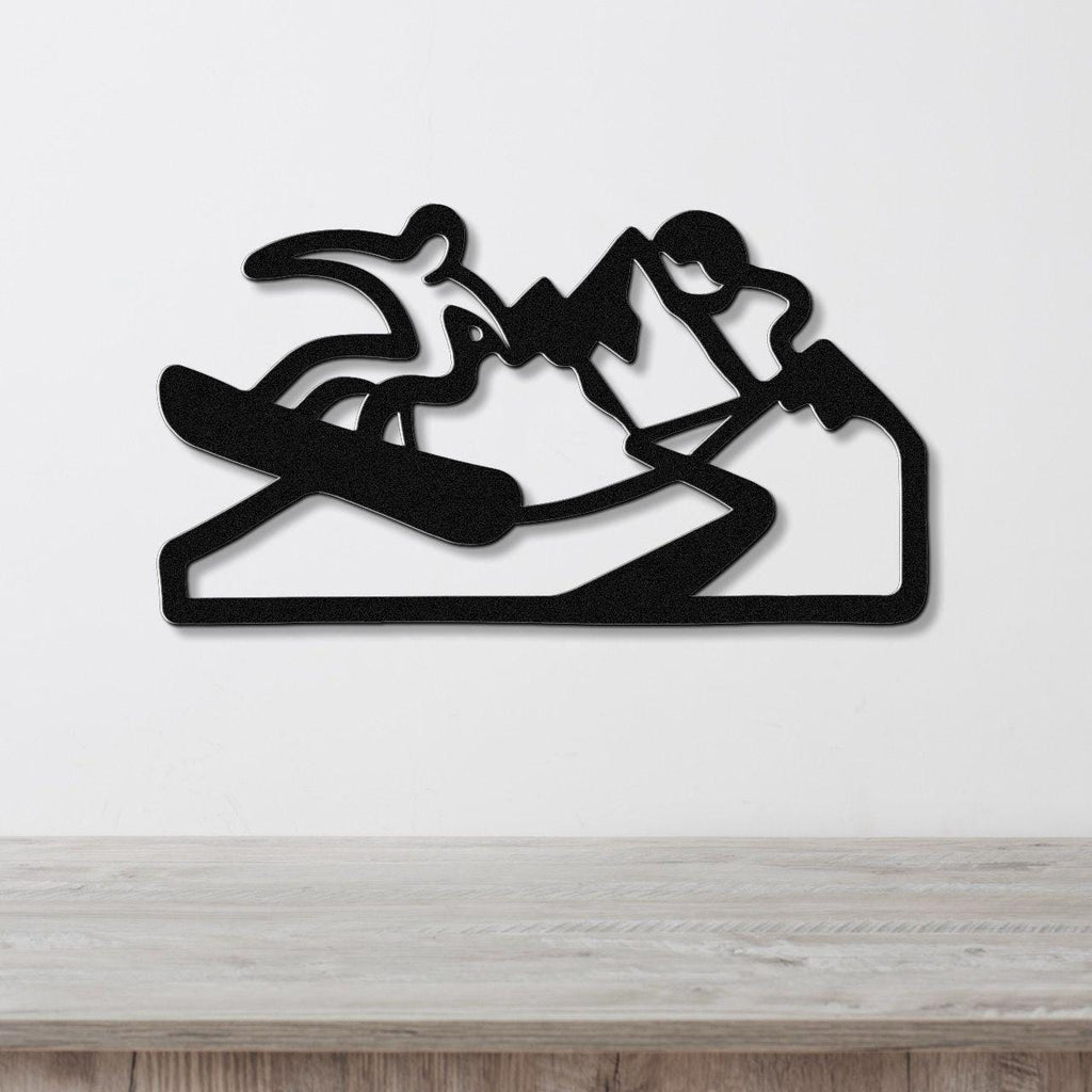 Black metal wall art silhouette of a snowboarder in motion, mounted on a white wall above a light wood counter.