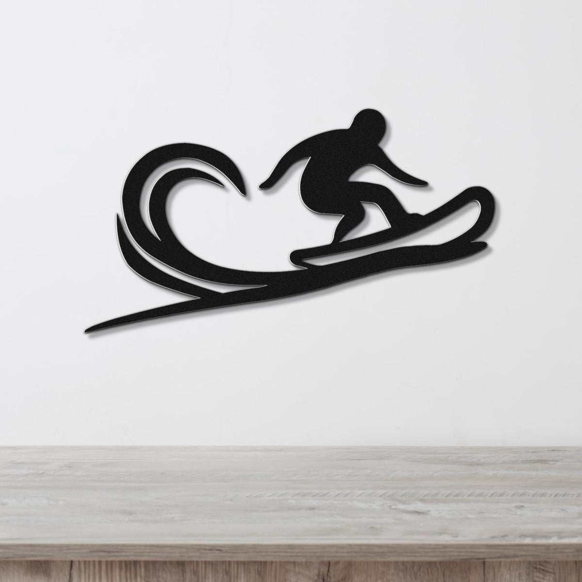 Black metal wall art silhouette of a snowboarder on a wave-shaped board, mounted on a white wall above a wooden counter.