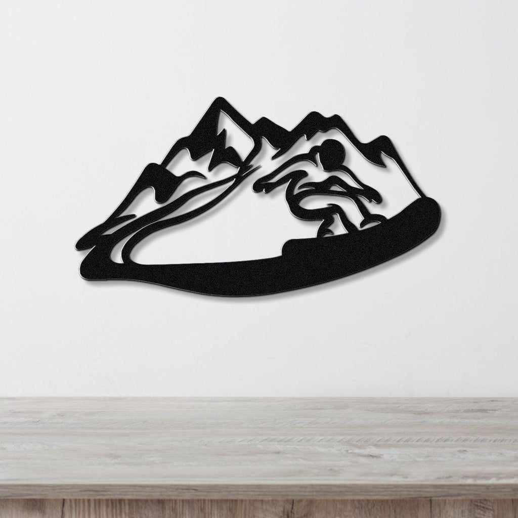 Black metal wall art featuring a snowboarder silhouette cutting through a mountain range, mounted on a white wall above a wooden counter.