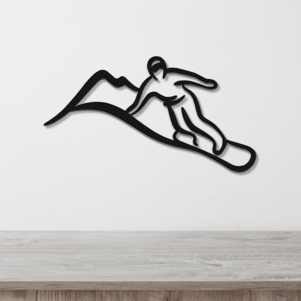 Black metal wall art silhouette of a snowboarder in motion, mounted on a white wall above a light wood surface.