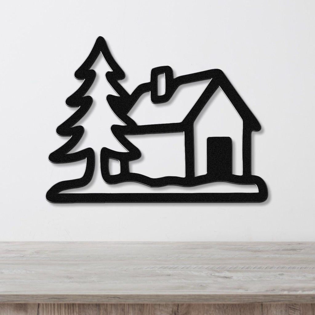 Black metal wall art silhouette of a cabin and pine tree, mounted on a white wall above a wooden surface.