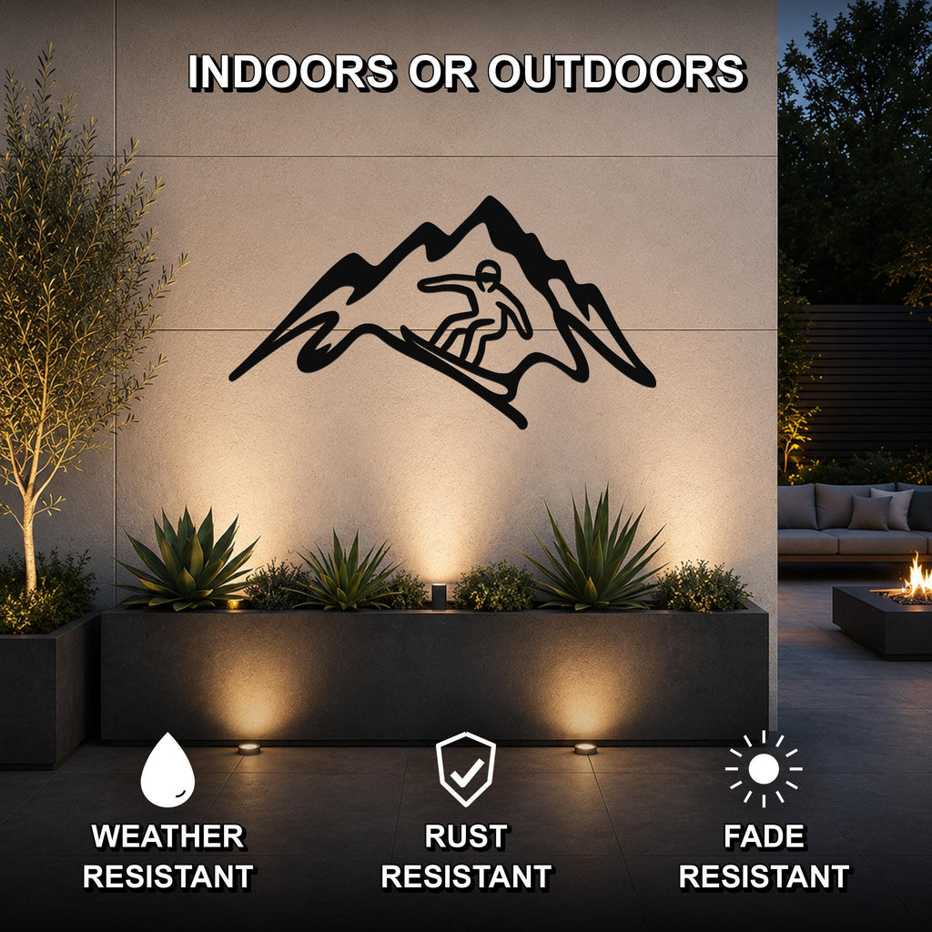 Black metal wall art featuring a snowboarder silhouette within a mountain cutout, mounted on an outdoor wall above a planter in a patio setting.