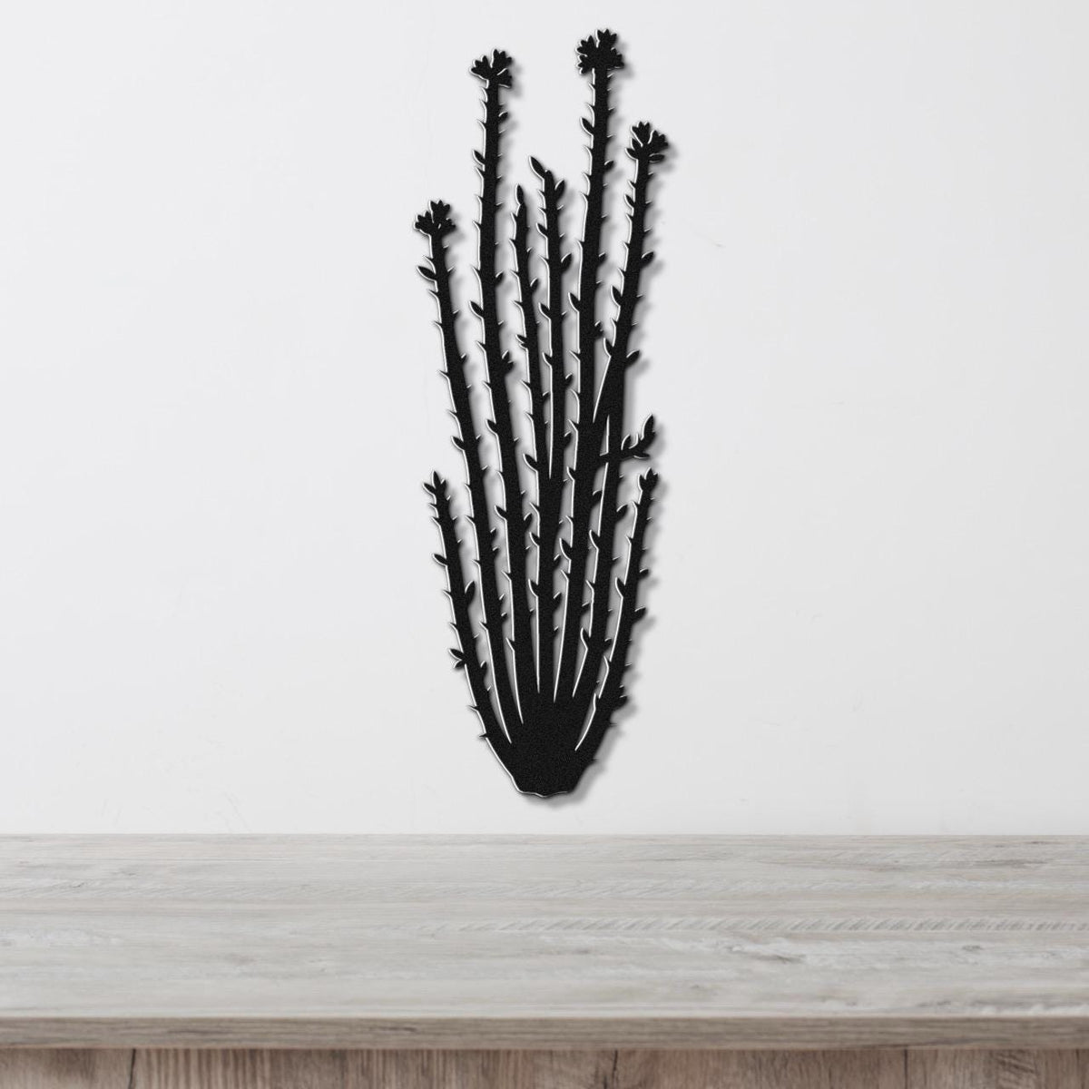 Black metal ocotillo wall art with spiny branches and flower cutouts, mounted on a white wall above a light wood counter.