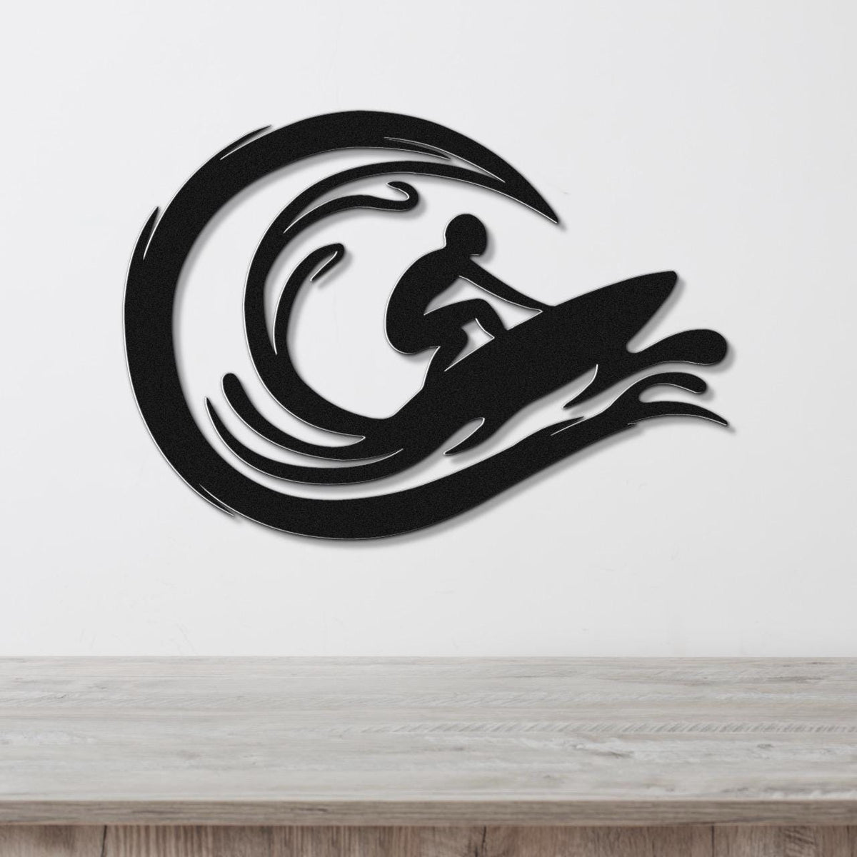 Black metal wall art featuring a surfer silhouette riding a wave, mounted on a white wall above a wooden surface.