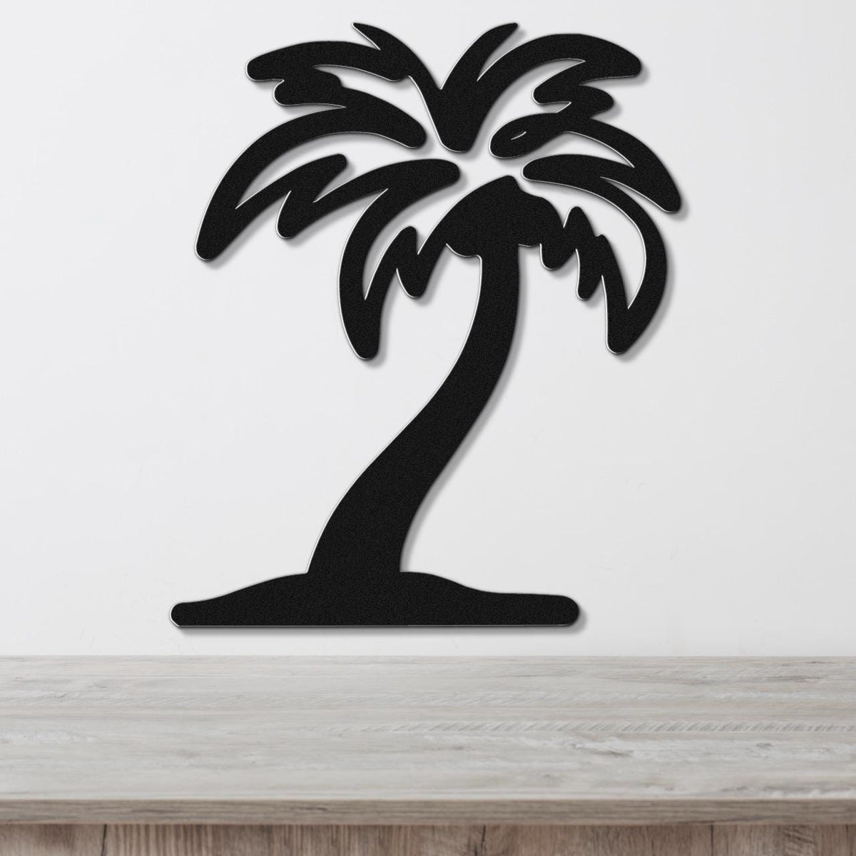 Black metal palm tree wall art with a silhouette design, mounted on a white wall above a wooden surface.