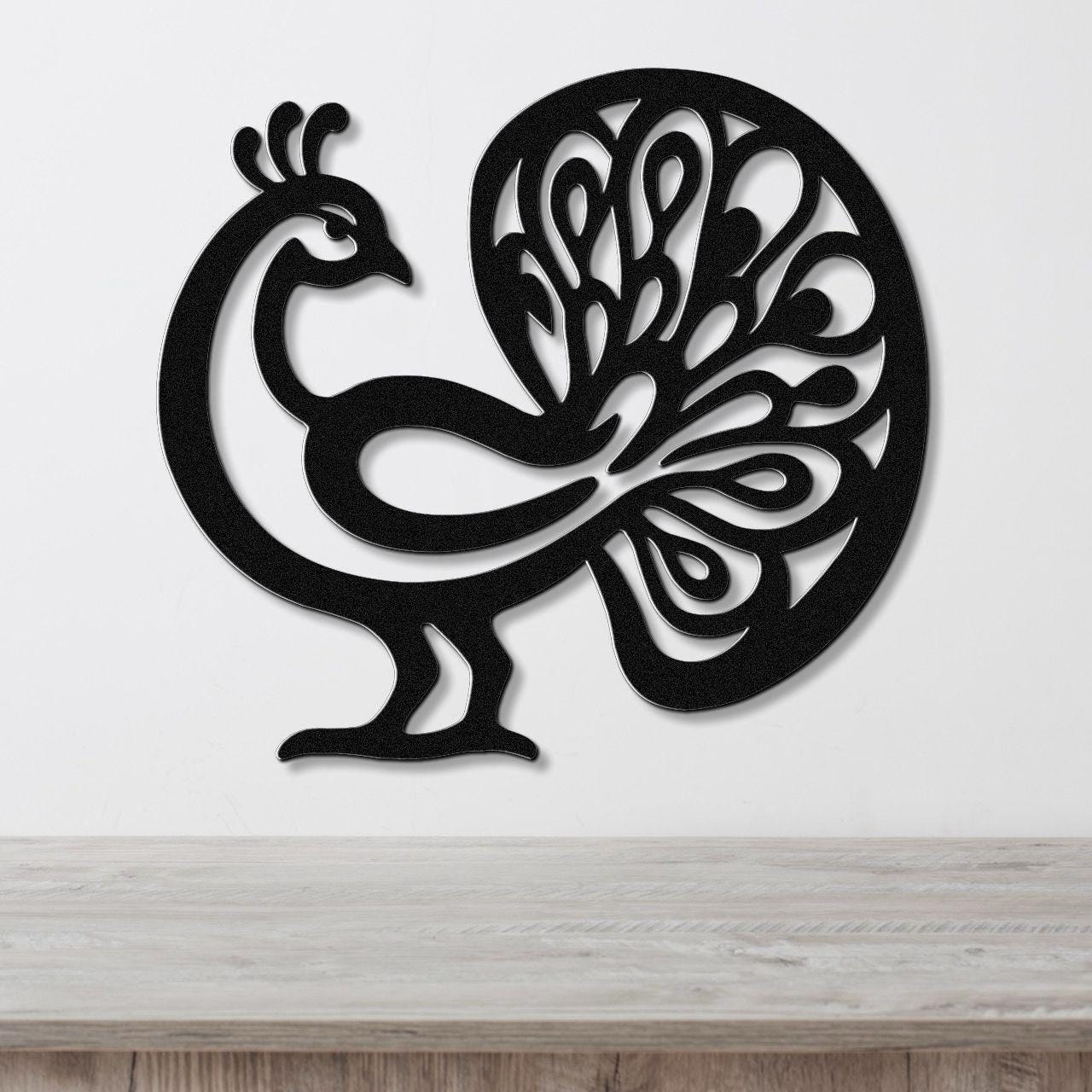 Black metal peacock wall art with intricate feather cutouts, mounted on a white wall above a wooden surface.