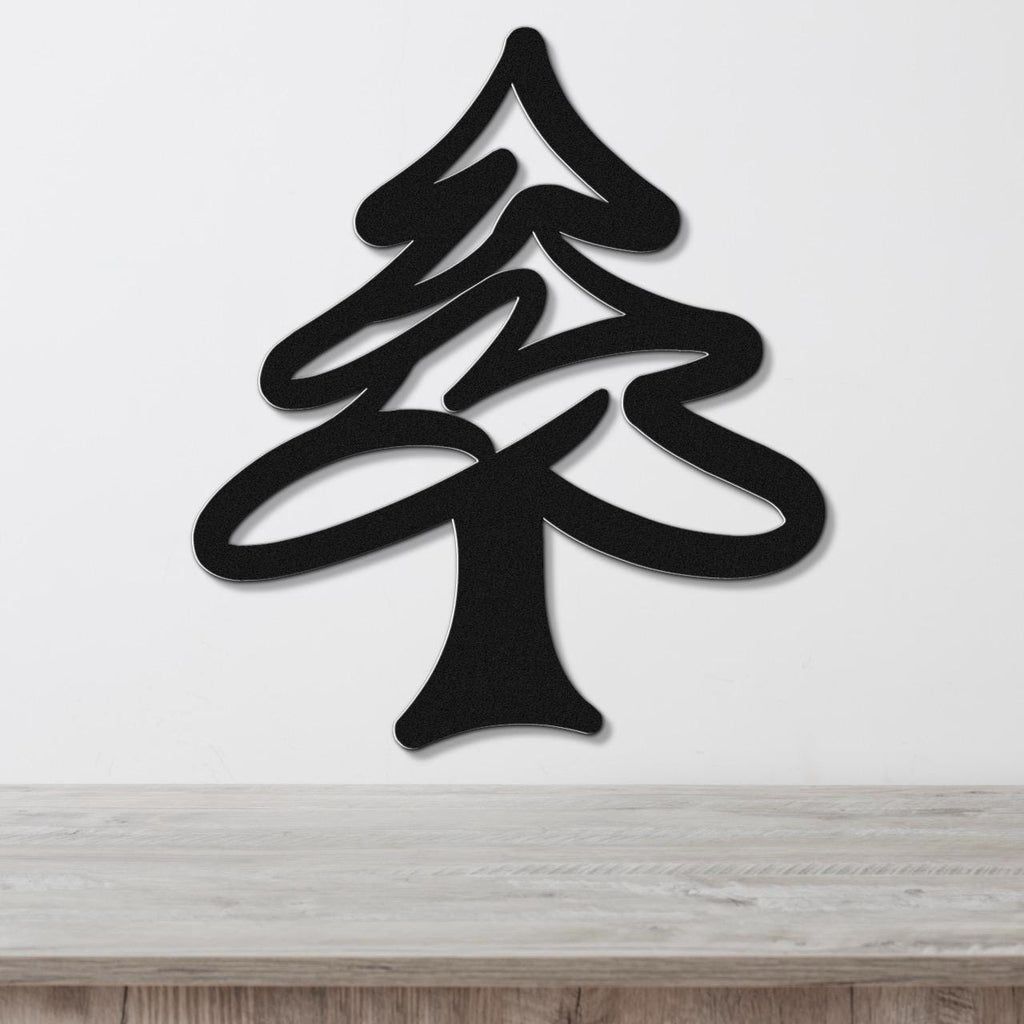 Black metal pine tree wall art with layered branch cutouts, mounted on a white wall above a light wood surface.