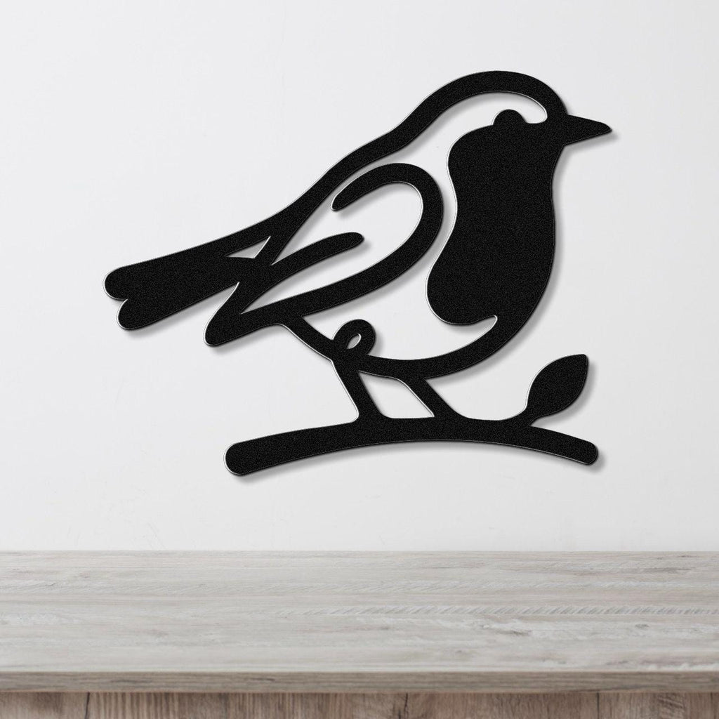 Black metal robin wall art silhouette perched on a branch, mounted on a white wall above a light wood counter.