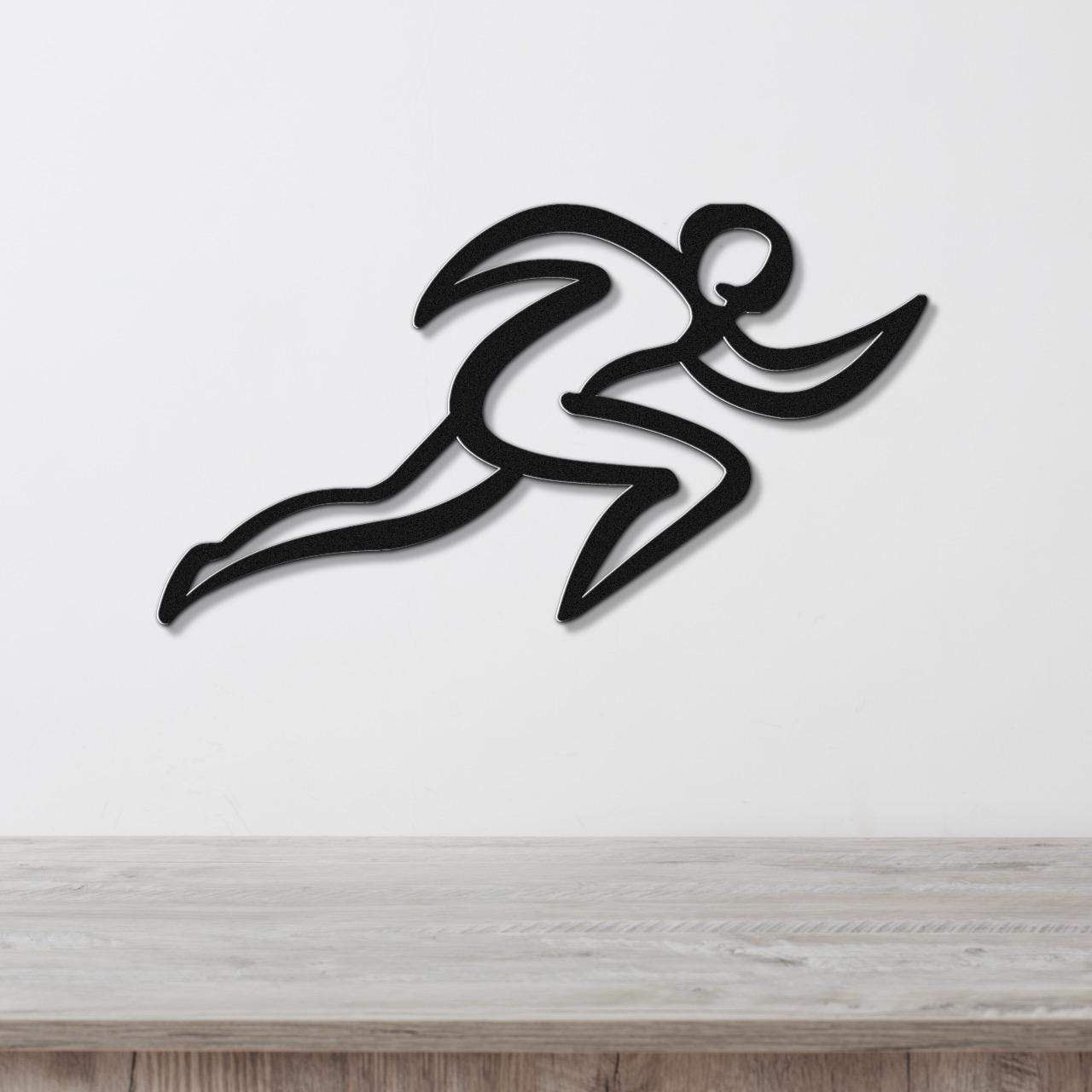 Black metal runner wall art with motion-line cutouts, mounted on a white wall above a wooden counter.