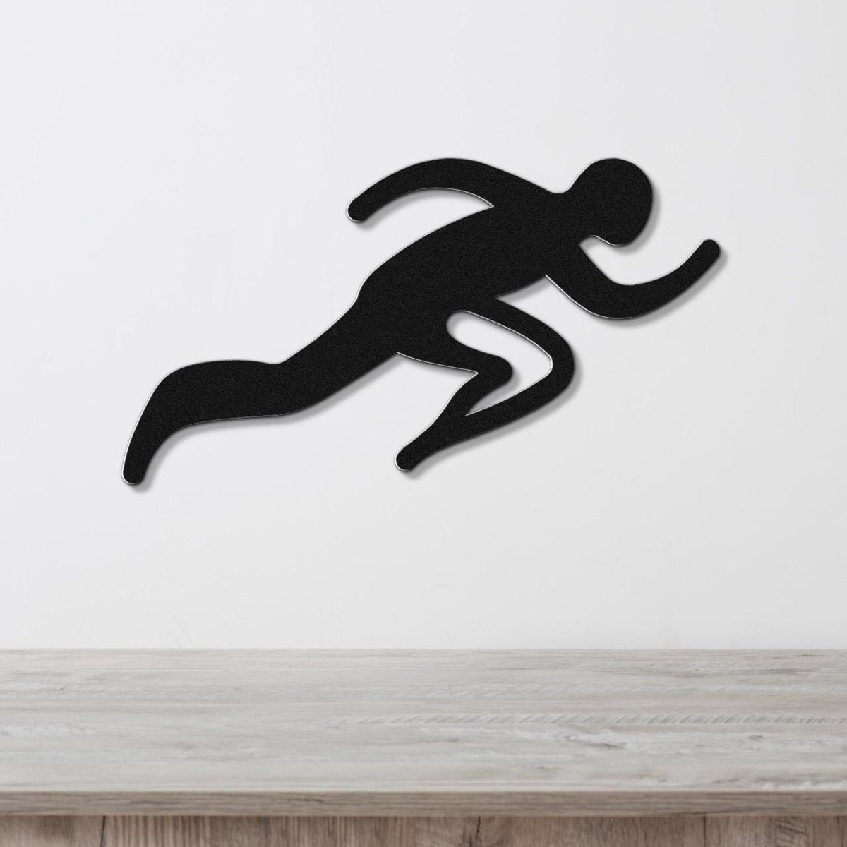 Black metal runner wall art with motion-line cutouts, mounted on a white wall above a light wood counter.