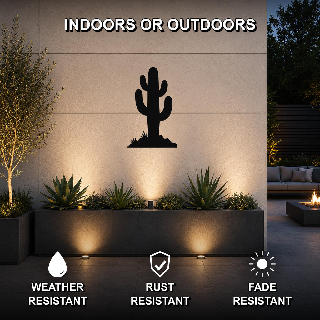 Black metal saguaro cactus wall art silhouette mounted on an outdoor wall above a planter, illuminated by uplights in a modern patio setting.