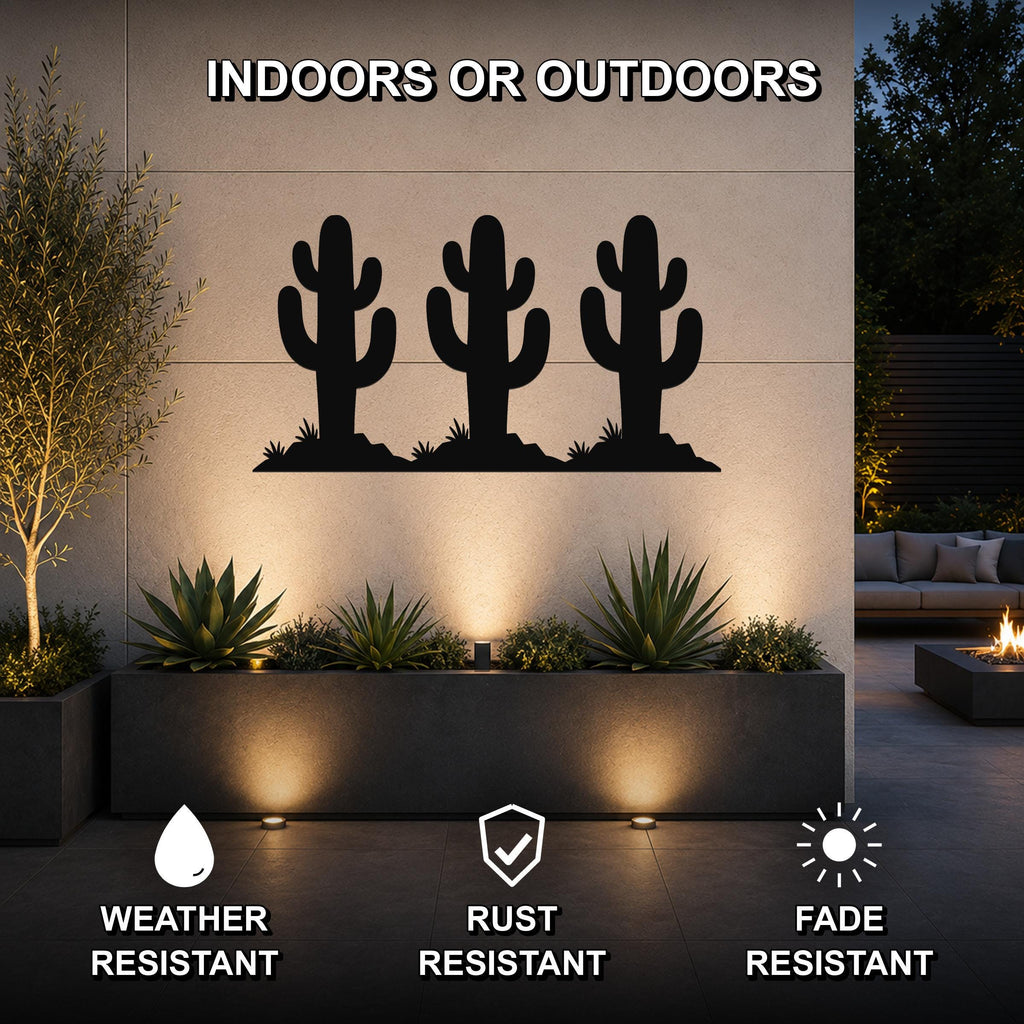 Black metal wall art featuring a silhouette of three saguaro cacti, mounted on an outdoor wall above a planter in a modern patio setting.