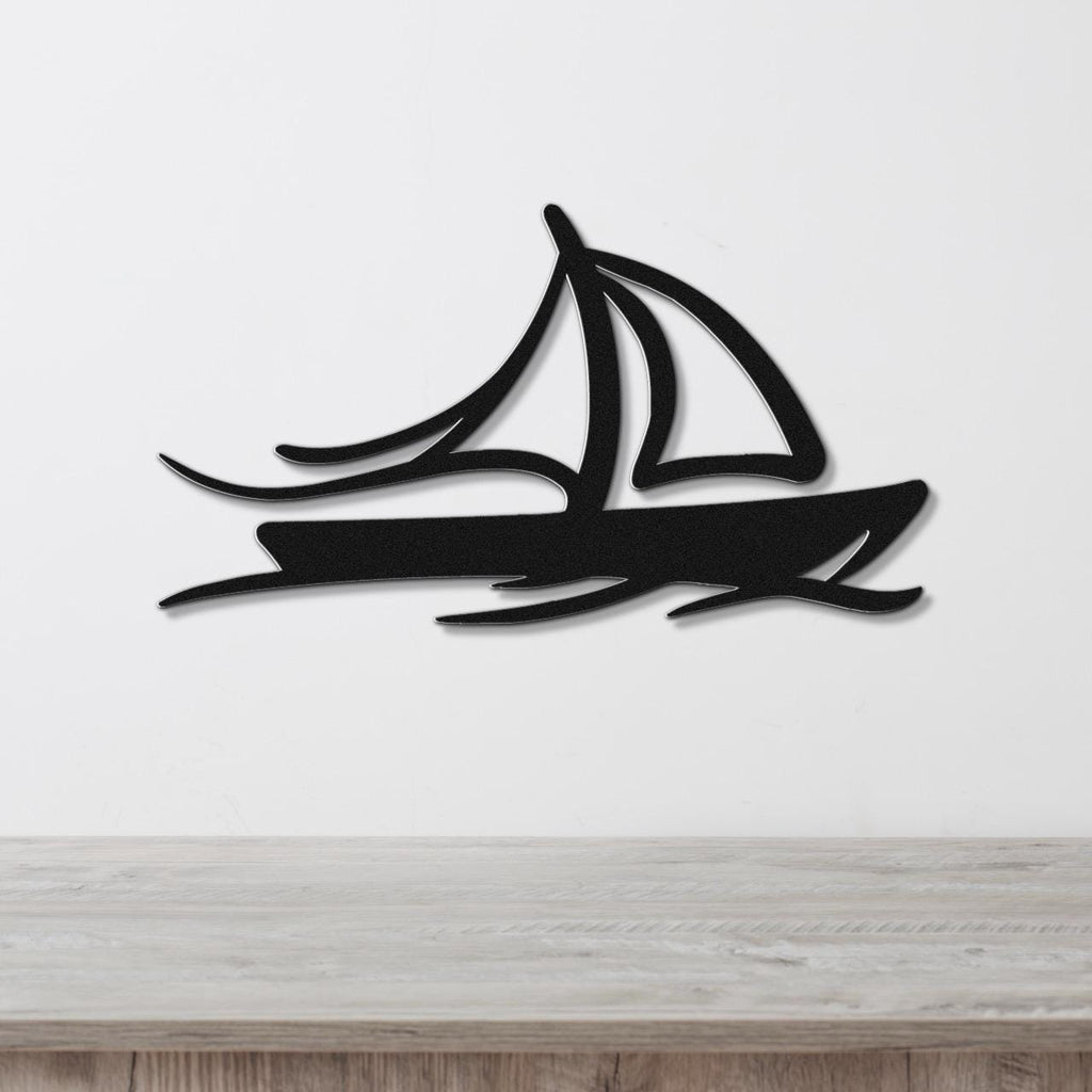 Black metal sailboat wall art with motion-line cutouts, mounted on a white wall above a light wood counter.