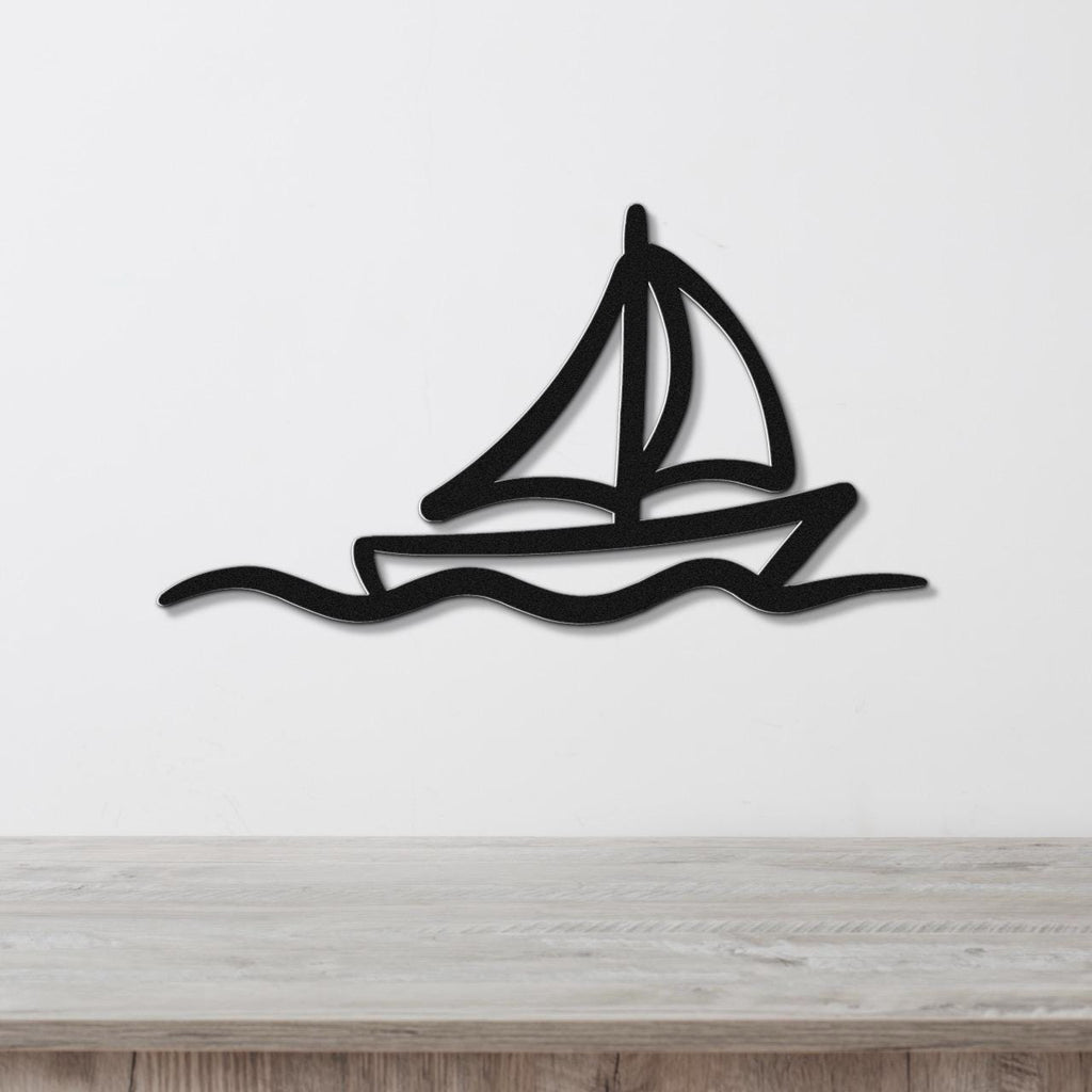 Black metal sailboat wall art with wave cutout, mounted on a white wall above a light wood counter.