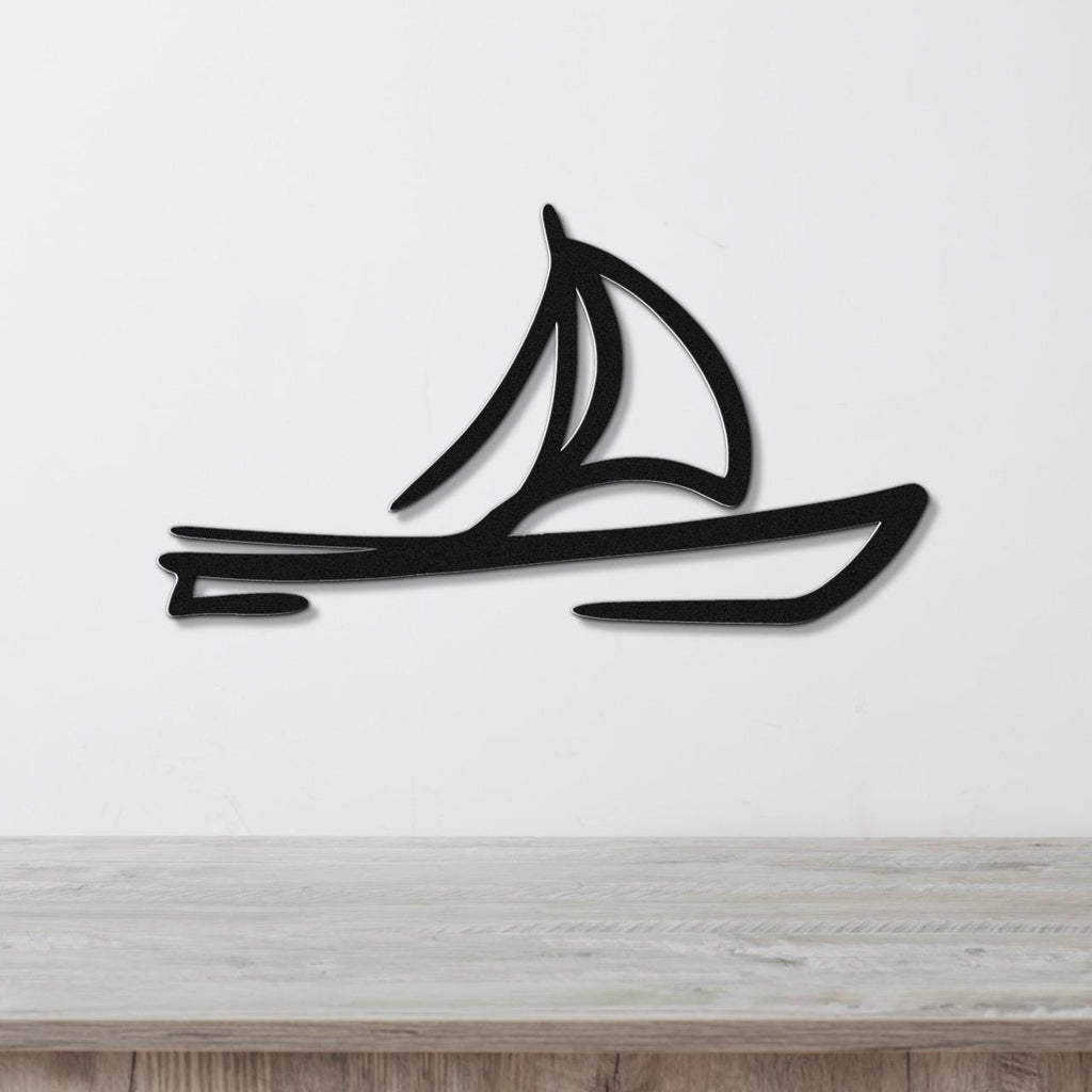 Black metal sailboat wall art with a silhouette design, mounted on a white wall above a wooden surface.