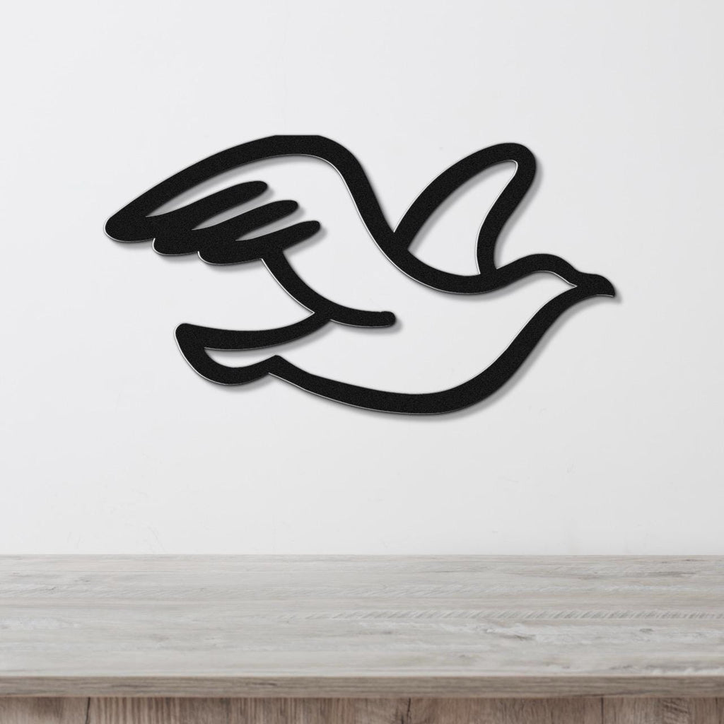 Black metal seagull wall art with a cutout silhouette design, mounted on a white wall above a light wood surface.
