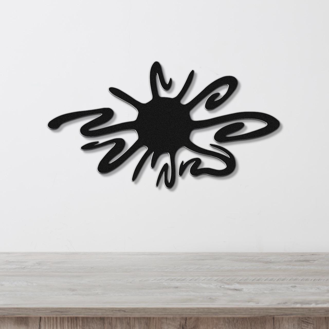 Black metal wall art in a sea urchin silhouette with flowing spines, mounted on a white wall above a light wood surface.