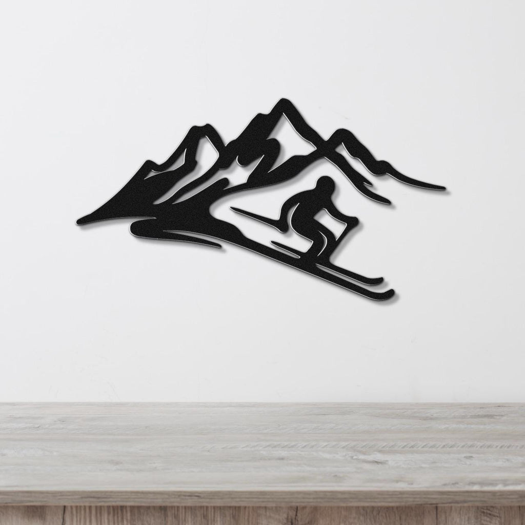 Black metal wall sculpture of a skier in motion against mountain peaks, mounted on a white wall above a wooden surface.